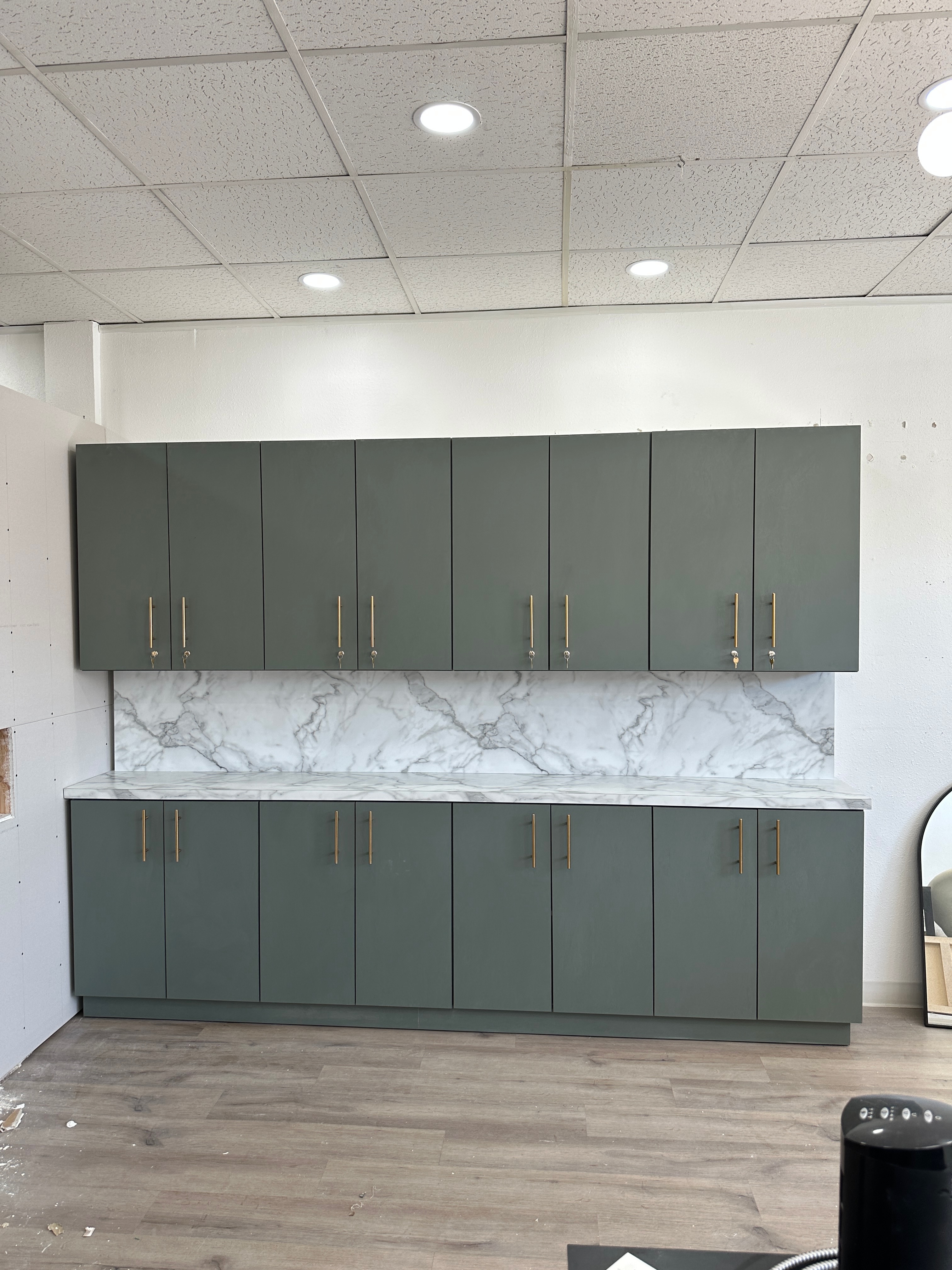 Sage green cabinets with gold handles and white marble counter and backsplash