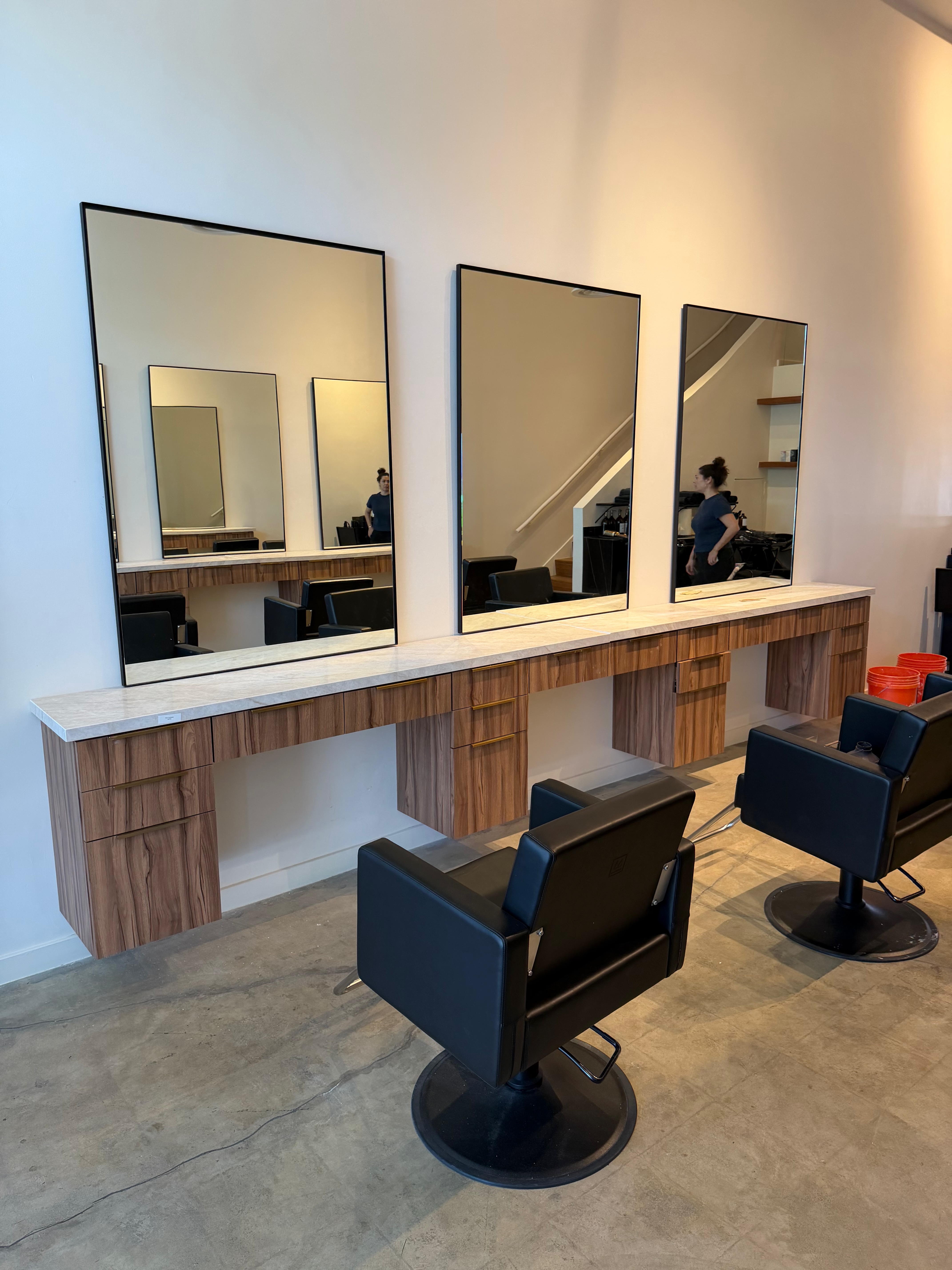 Black-framed mirror styling stations with wood base cabinets
