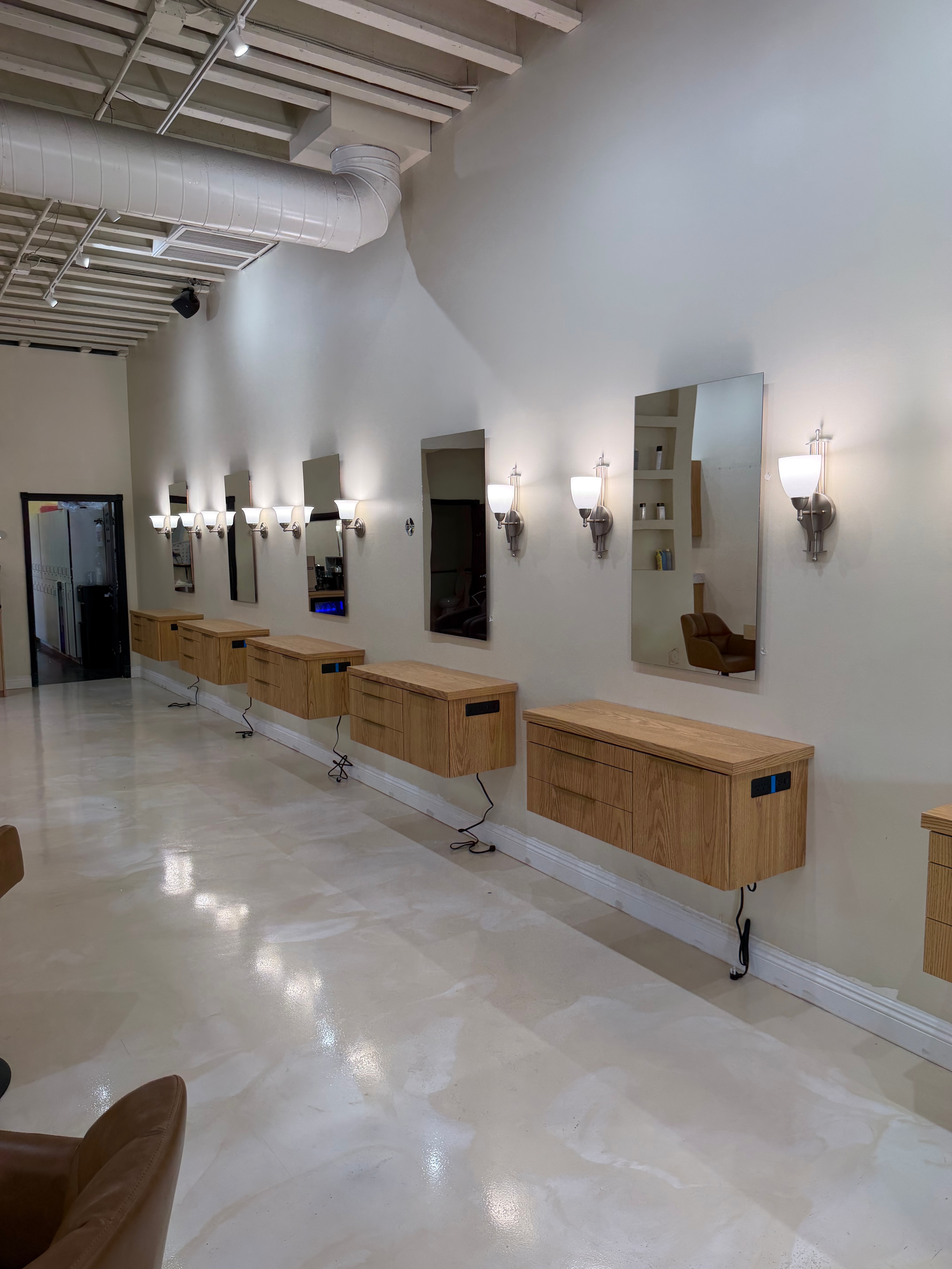 Wide view of a salon floor with a row of wood styling stations
